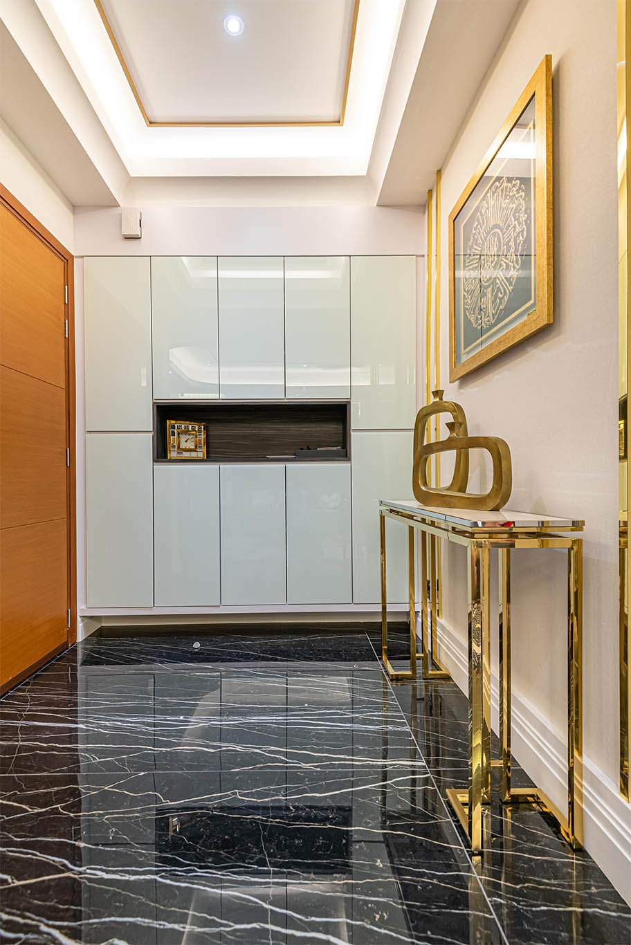 Luxurious hallway with Islamic Art with gold frame, hidden light, black marble tiles, and white minimalist cabinet