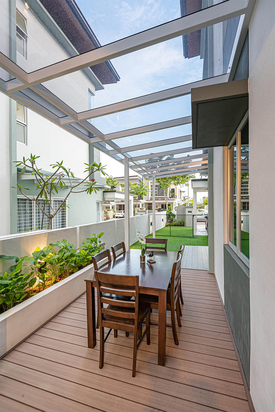 Outdoor decoration with transparent glass awning, wooden floor and table, and some green plants